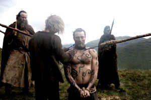 One-Eye (Mads Mikkelsen), todavía esclavo, siendo preparado para una lucha a muerte organizada por el clan de vikingos que le mantiene preso
