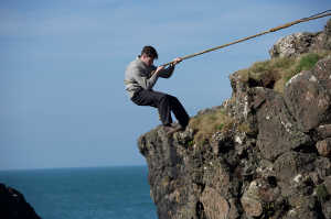 El joven Donald McArthur (Connor Swindells) bajando los acantilados rocosos de una isla desierta