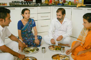 Ratna junto al resto de la servidumbre comiendo en el suelo de la cocina en la casa de Ashwin, donde todos trabajan